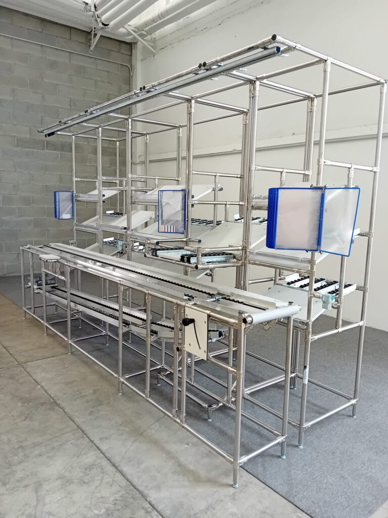 Linea di assemblaggio industriale con piano a rulli, alimentazione FIFO e ripiani Kanban per l'organizzazione del flusso produttivo.